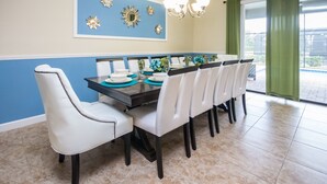 A dining area with a long table, white chairs, and blue wall decor. - Providence 2401 (Davenport)