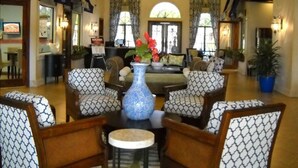 A spacious lobby with patterned chairs, a central table with a vase, and a large clock on the wall. - Paradise Palms 8959 (Kissimmee)