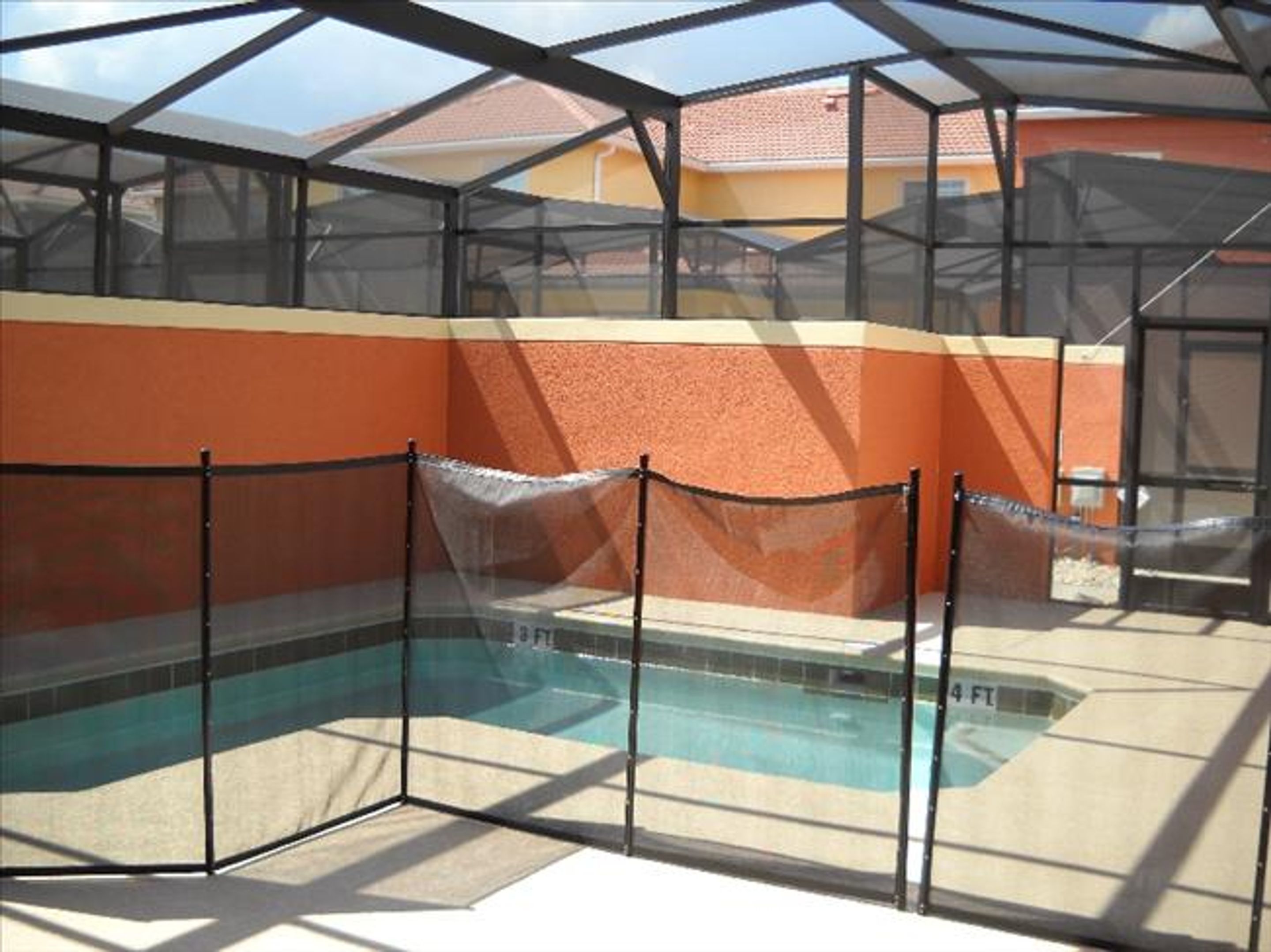 A swimming pool with a glass enclosure and a rope barrier.