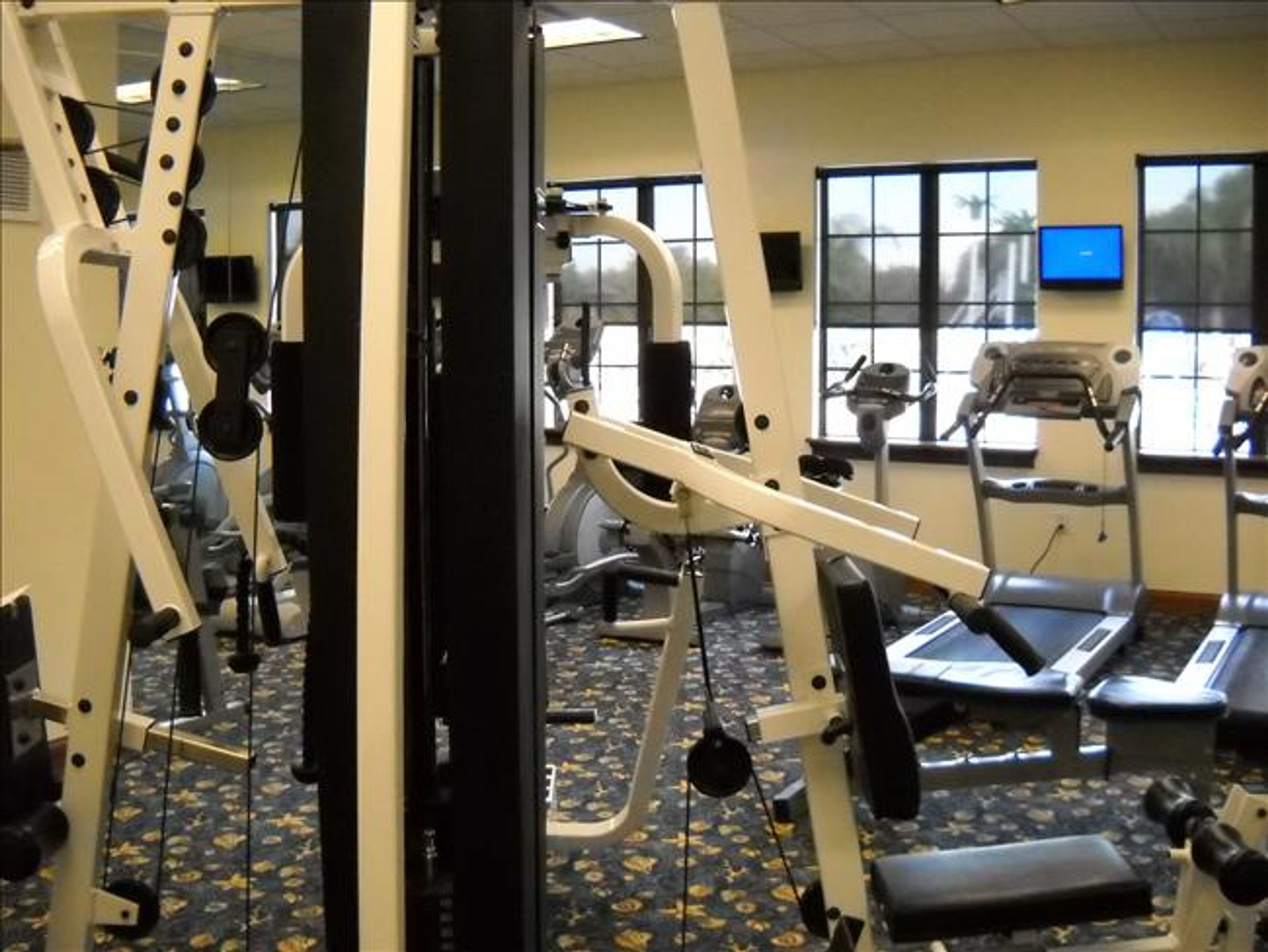 Une salle de sport équipée de divers appareils d’exercice, d’un tapis de course et d’un écran de télévision.