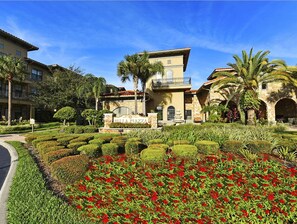 A hotel with a landscaped garden, a sign reading "Bella Piazza," and a stone building with a balcony. - Bella Piazza 907 - 926 (Davenport)