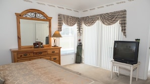 A bedroom with a large bed, a dresser, a television on a stand, and a window with curtains. - Westridge 1007 (Davenport)