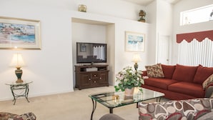 A living room with a sofa, armchair, glass coffee table, TV, and decorative items. - Westridge 1007 (Davenport)