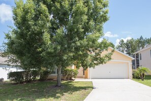 A residential property with a garage, a lawn, and a large tree. - Westridge 1007 (Davenport)