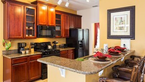 A kitchen with wooden cabinets, a black refrigerator, and granite countertops.