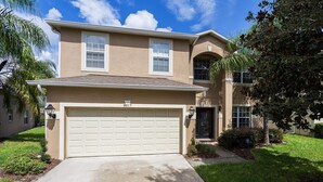 A two-story house with a beige exterior, a garage number 8017, and a well-maintained lawn.
