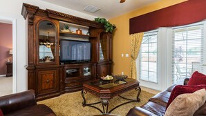 A living room with a large wooden entertainment center, leather sofa, and a glass coffee table.