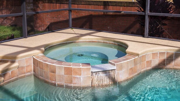 A hot tub with a tiled edge and a small waterfall feature.
