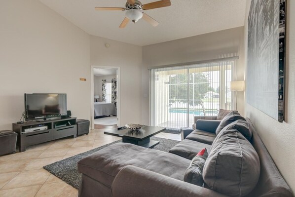 A living room with a sofa, TV, and ceiling fan.