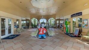 A covered outdoor area with a ceiling fan, lounge chairs, and a mascot statue. - Windsor Hills 7675 - 303 (Kissimmee)