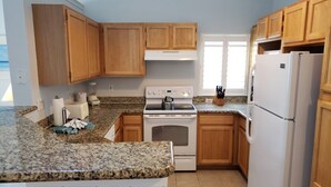 Une cuisine avec des meubles de rangement en bois, une cuisinière blanche et un réfrigérateur.