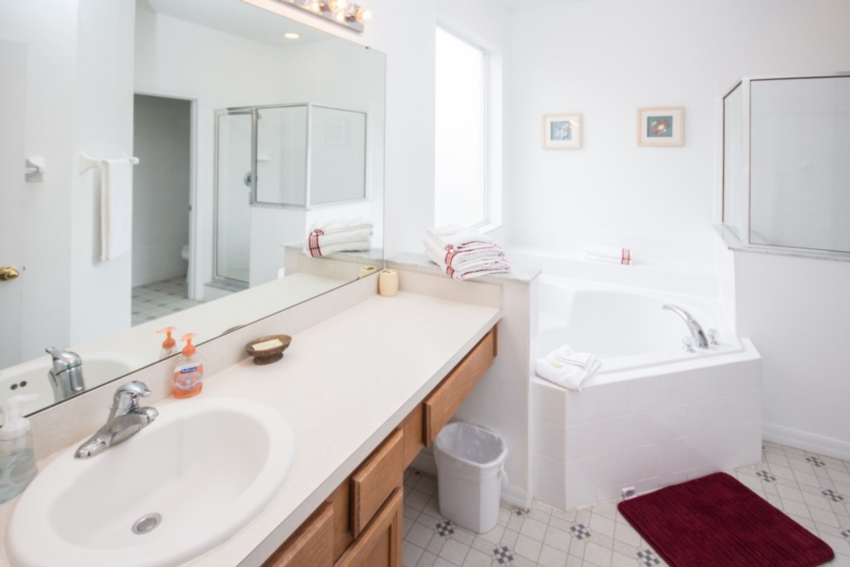 Une salle de bain moderne avec un grand miroir, deux lavabos, une baignoire et une douche.