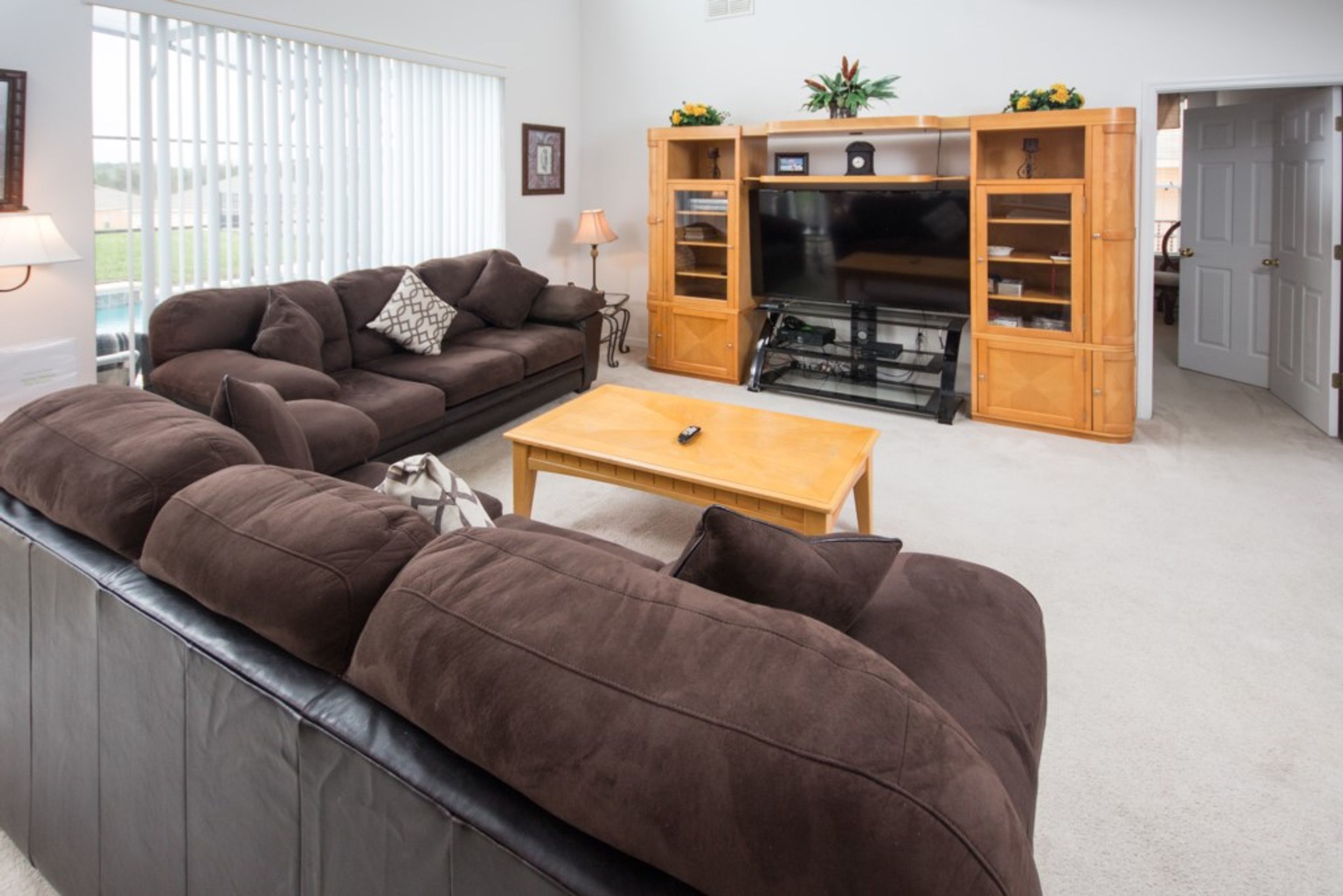 Ein Wohnzimmer mit braunem Sofa, einem Holztisch und einer TV-Konsole mit Regalen.
