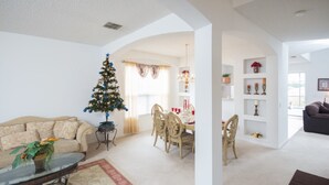 Ett vardagsrum med en julgran, en matplats och en soffa.