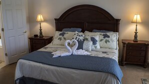 A neatly made bed with a blue and white bedspread, two bedside lamps, and floral pillows. - High Gate Park 938 (Davenport)
