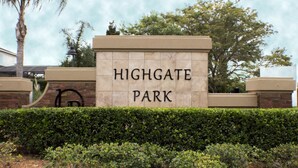 A sign for Highgate Park with a brick wall and greenery in the background. - High Gate Park 938 (Davenport)