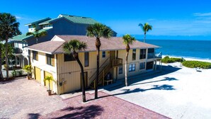 Une propriété située en bord de mer, comprenant un bâtiment à deux étages, un escalier et une vue sur la plage.