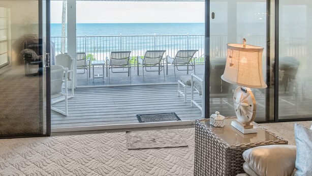 Un balcon avec vue sur l’océan, aménagé avec des chaises et une table.