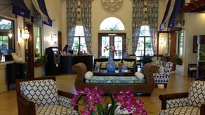 A lobby with a reception desk, patterned sofas, and a large vase with flowers. - Paradise Palms 8965 Candy (Kissimmee)