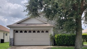 Ein eingeschossiges Haus mit Garage, Nummer 2667, umgeben von einem gepflegten Rasen und einem großen Baum.