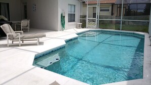 Ein Schwimmbecken mit überdachter Terrasse, Liegestühlen und einem Schlauch zum Befüllen.