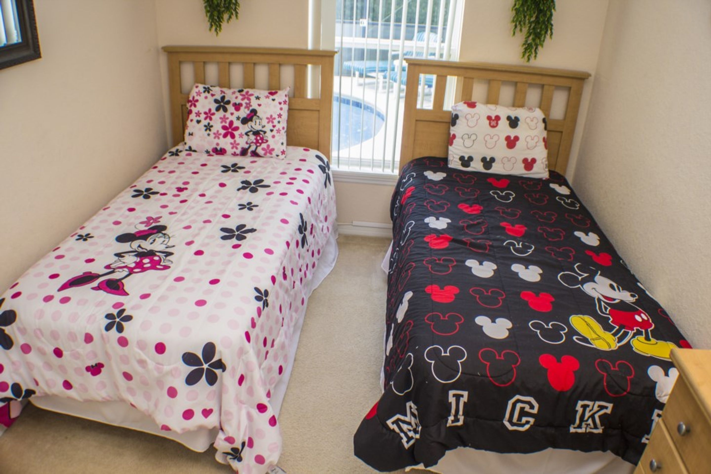 Een slaapkamer met twee eenpersoonsbedden, elk met een beddeken met een Mickey Mouse thema.