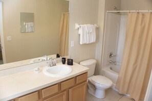 A bathroom with a sink, mirror, toilet, and bathtub. - Coral Cay 2412 (Kissimmee)