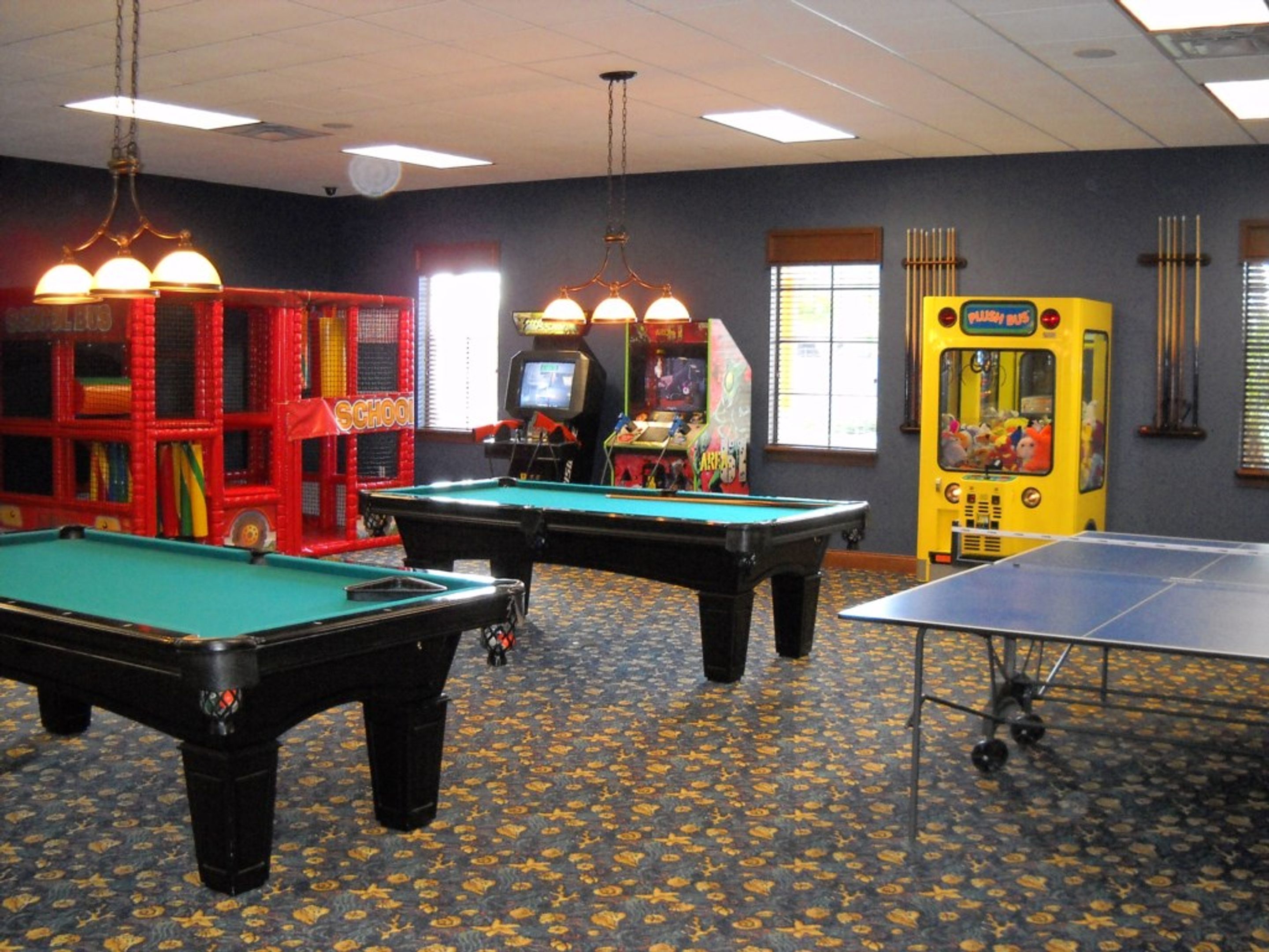 A room with pool tables, arcade games, and a ping pong table.