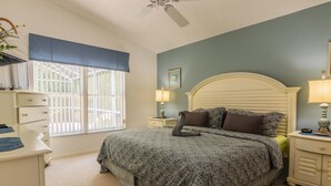 A bedroom with a large bed, a desk, and a window with blinds. - Lindfields 3002 (Kissimmee)