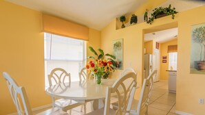 A dining area with a round table, white chairs, and a vase of flowers. - Lindfields 3002 (Kissimmee)
