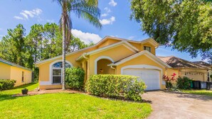 A two-story house with a yellow facade, a garage, and a well-maintained lawn. - Lindfields 3002 (Kissimmee)