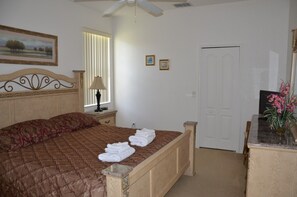 A bedroom with a bed, a nightstand, a lamp, a door, and a small table with a vase. - Highlands Reserve Golf & Country Club 448 (Davenport)