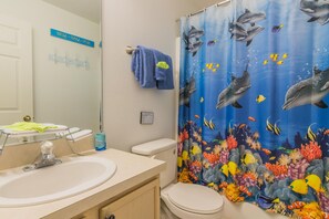 A bathroom with a sink, toilet, and a shower curtain with a marine life theme.