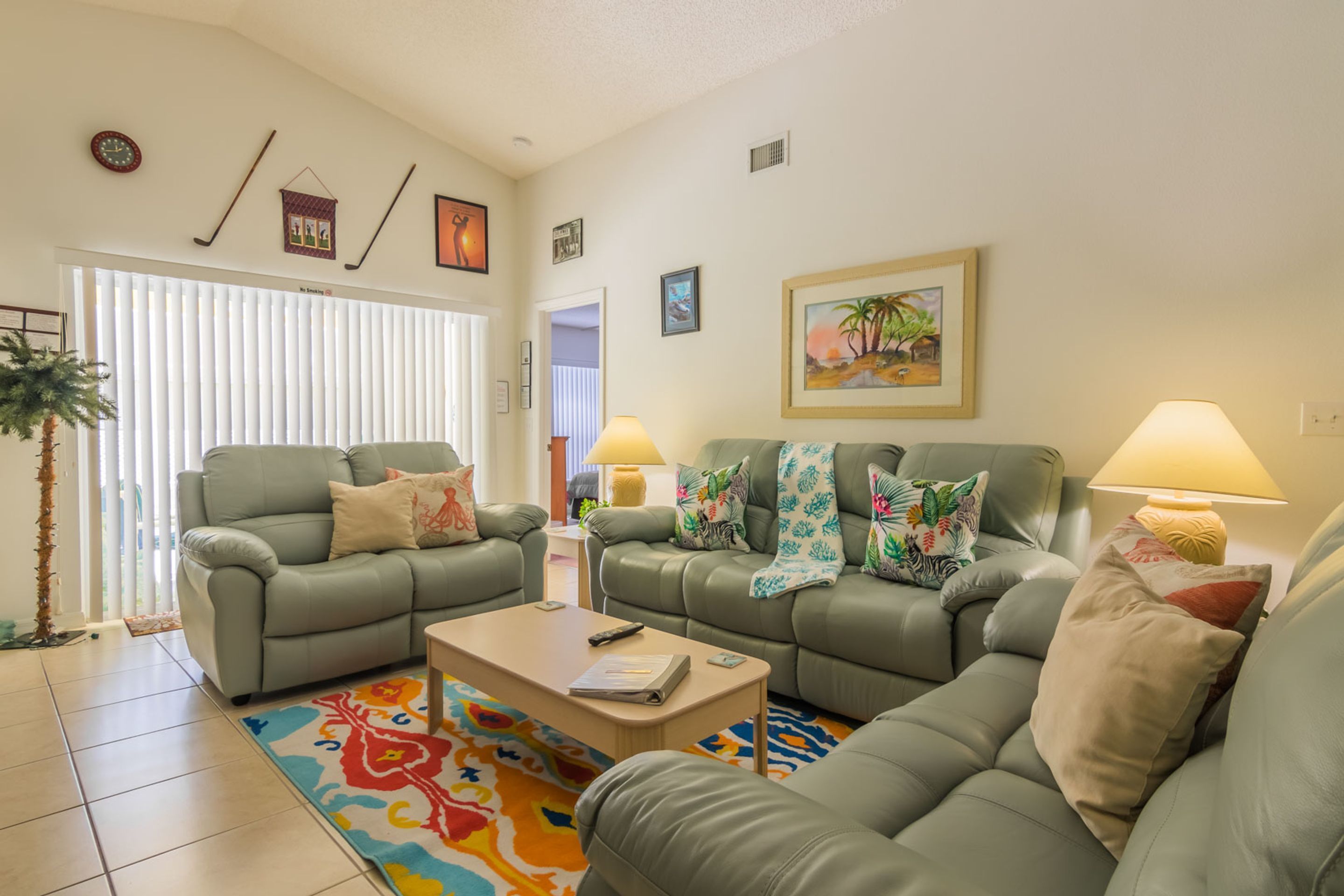 A living room with two green sofas, a coffee table, and a colorful rug.
