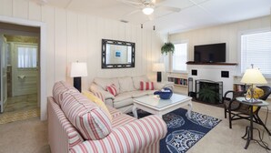 A living room with a striped sofa, a coffee table, a fireplace, and a television. - Fort Myers Beach Area 2670 (Fort Myers Beach)
