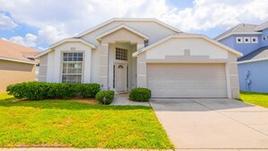 A single-story house with a garage, a front door, and a small front yard with bushes. - The Palms at Lake Davenport 647 (Davenport)