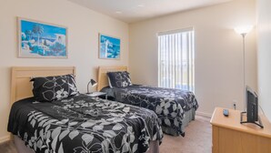A hotel room with two beds, a desk with a TV, and two paintings on the wall. - The Palms at Lake Davenport 647 (Davenport)