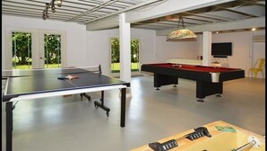 Un amplio espacio interior recreativo con mesa de ping pong, mesa de billar y mesa de futbolín.