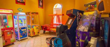 A room with arcade games, a window with a view, and a poster on the wall.