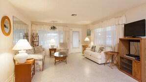 A living room with a sofa, armchairs, a coffee table, a TV stand, and a mirror. - Bonita Springs 92 (Bonita Springs)