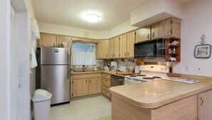 A kitchen with wooden cabinets, a stainless steel refrigerator, a microwave, and a stove. - Bonita Springs 92 (Bonita Springs)