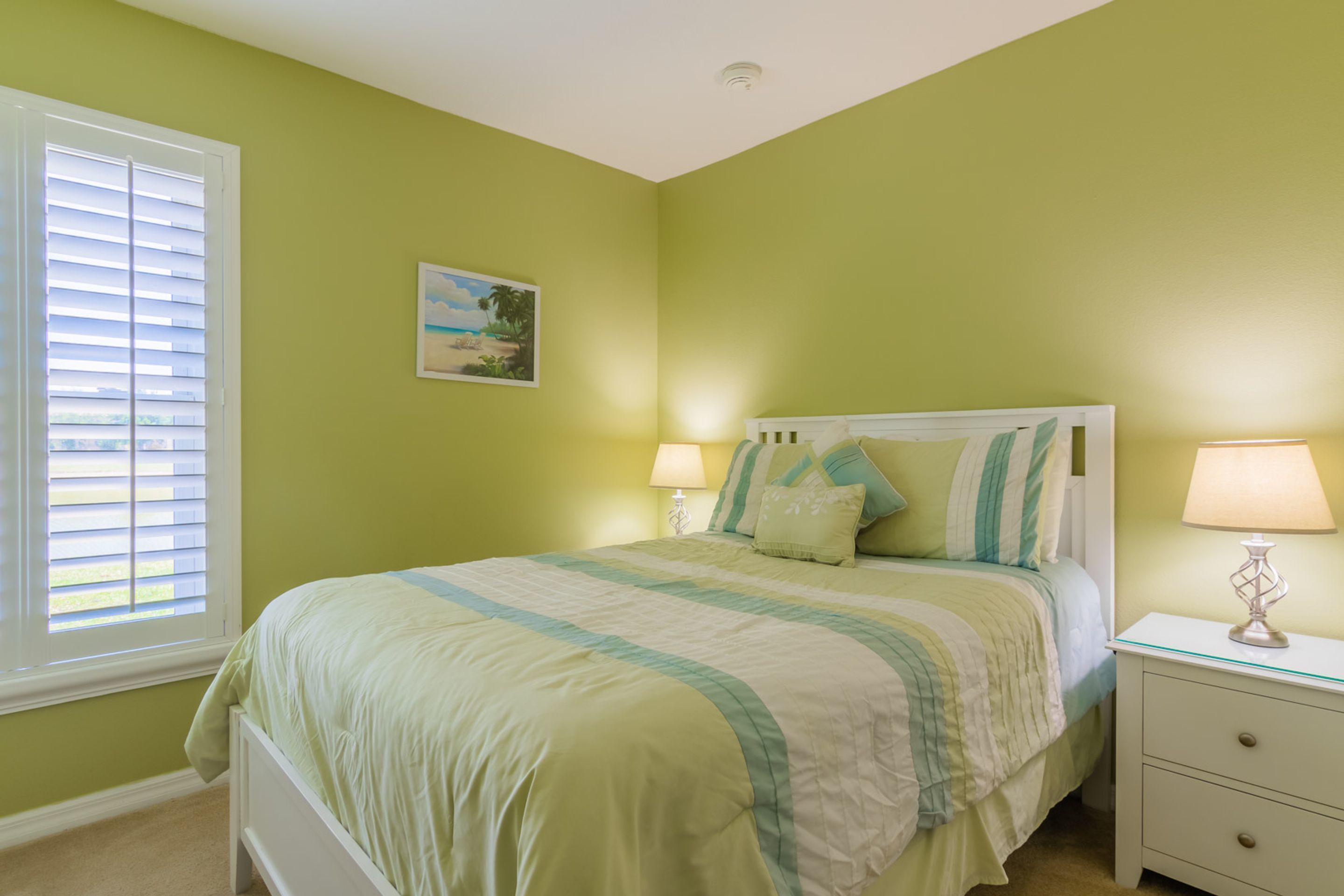 A bedroom with a bed, nightstands, and a window with blinds.