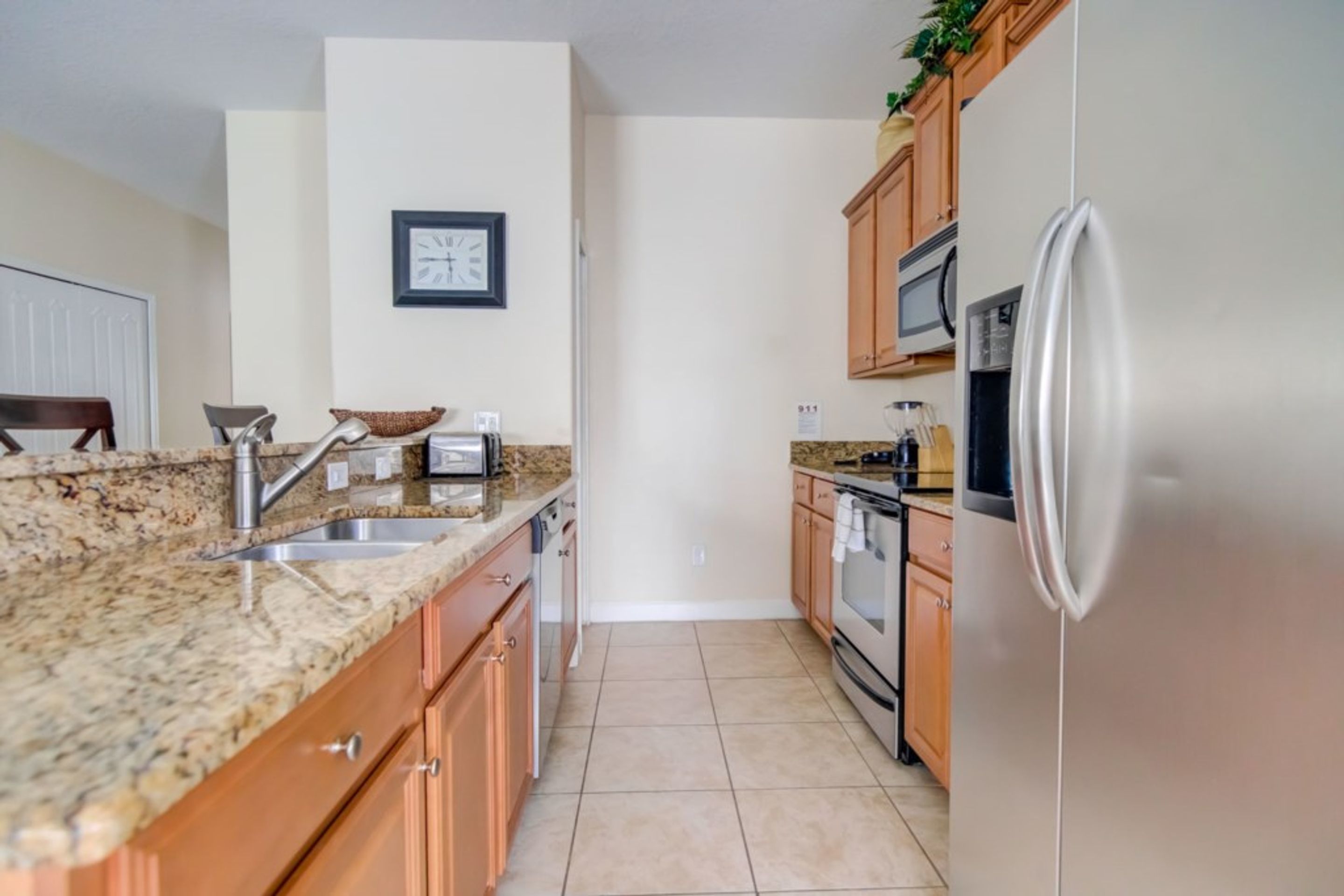 A kitchen with granite countertops, wooden cabinets, stainless steel appliances, and a tiled floor.