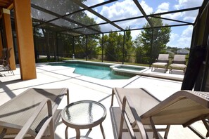 An outdoor pool area with lounge chairs and a glass table, surrounded by a covered patio. - The Shire at West Haven 883 (Davenport)