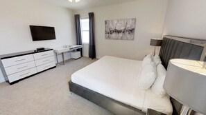 A modern hotel room with a large bed, a desk, a flat-screen TV, and a painting on the wall. - Encore Resort at Reunion 7705 (Kissimmee)