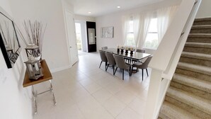 A modern dining area with a table and chairs, a staircase, and a door leading to another room. - Encore Resort at Reunion 7705 (Kissimmee)