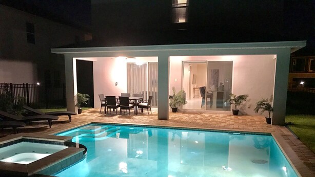 A swimming pool with a patio area, including a table and chairs, and a covered seating area. - Encore Resort at Reunion 7705 (Kissimmee)
