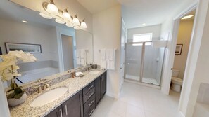 A modern bathroom with a double sink vanity, a large mirror, and a walk-in shower. - Encore Resort at Reunion 7705 (Kissimmee)