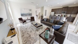A spacious living room with a grey sofa, a coffee table, and a modern kitchen in the background. - Encore Resort at Reunion 7705 (Kissimmee)