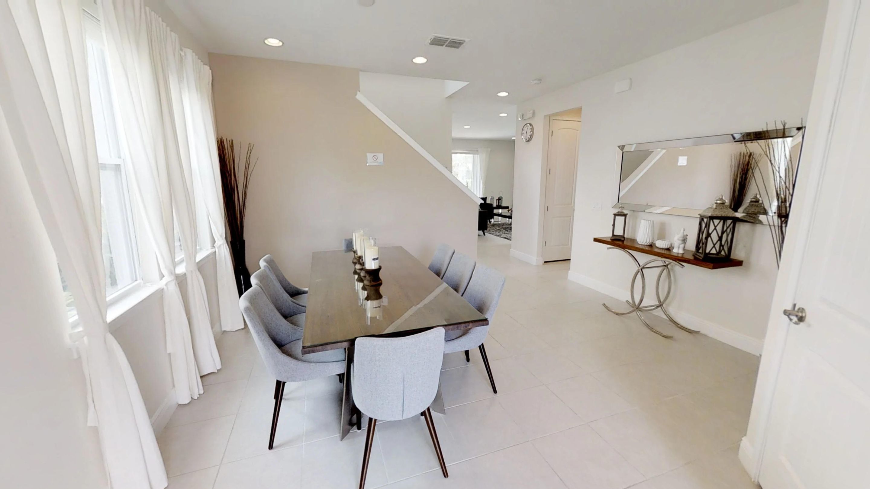 A dining area with a rectangular table, grey upholstered chairs, and a modern chandelier.